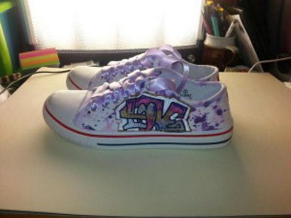 white canvas shoes has purple pink paint splotches and graffiti name on the side
