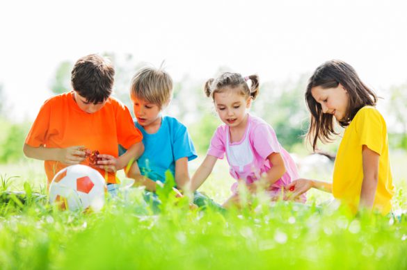 Cheerful kids sitting and playing in the park surrounded by beautiful nature.